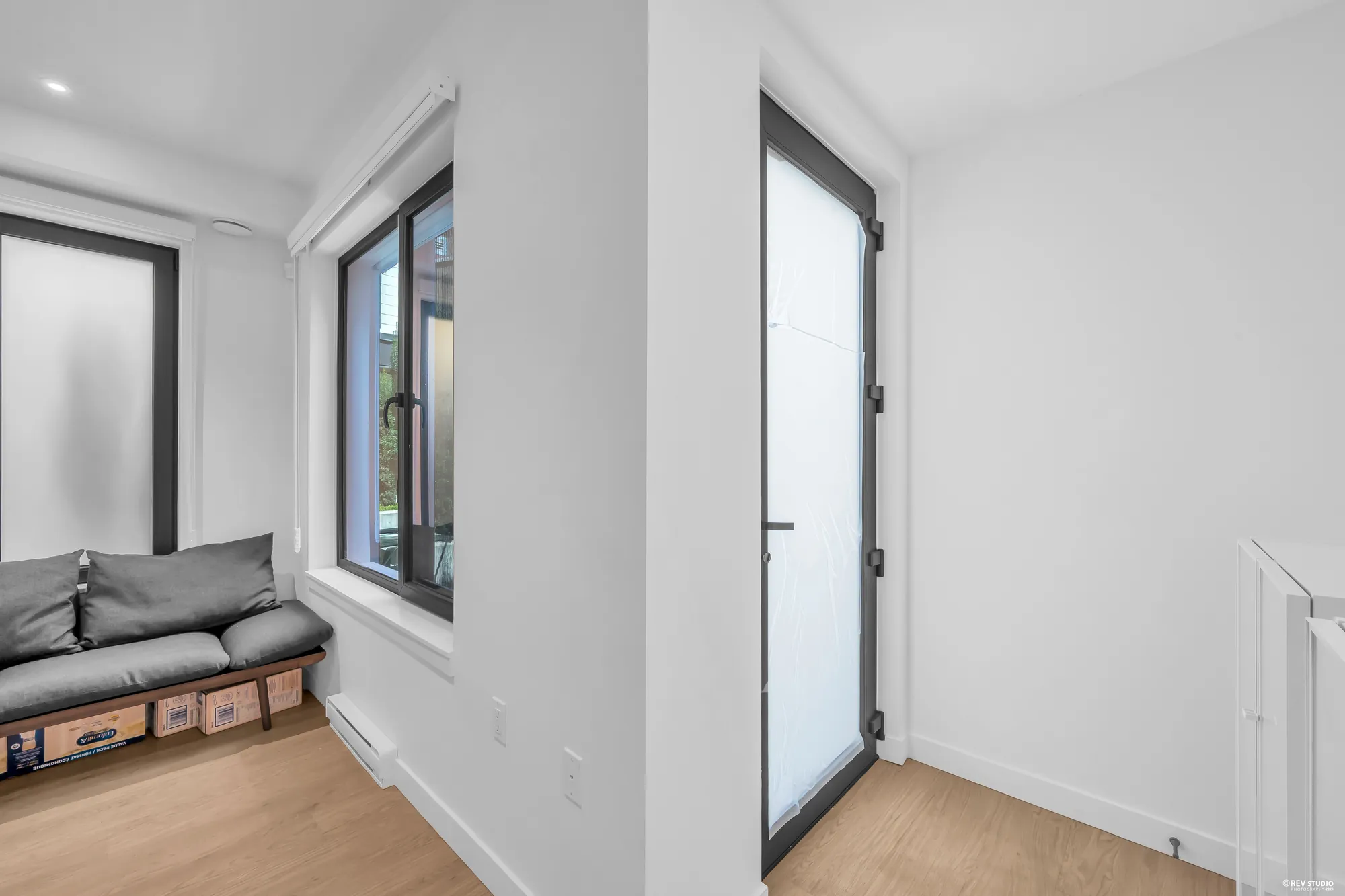 The foyer: a tall front door with a glass panel, a casement window beside it, a cushioned bench along the wall, wood-look floors