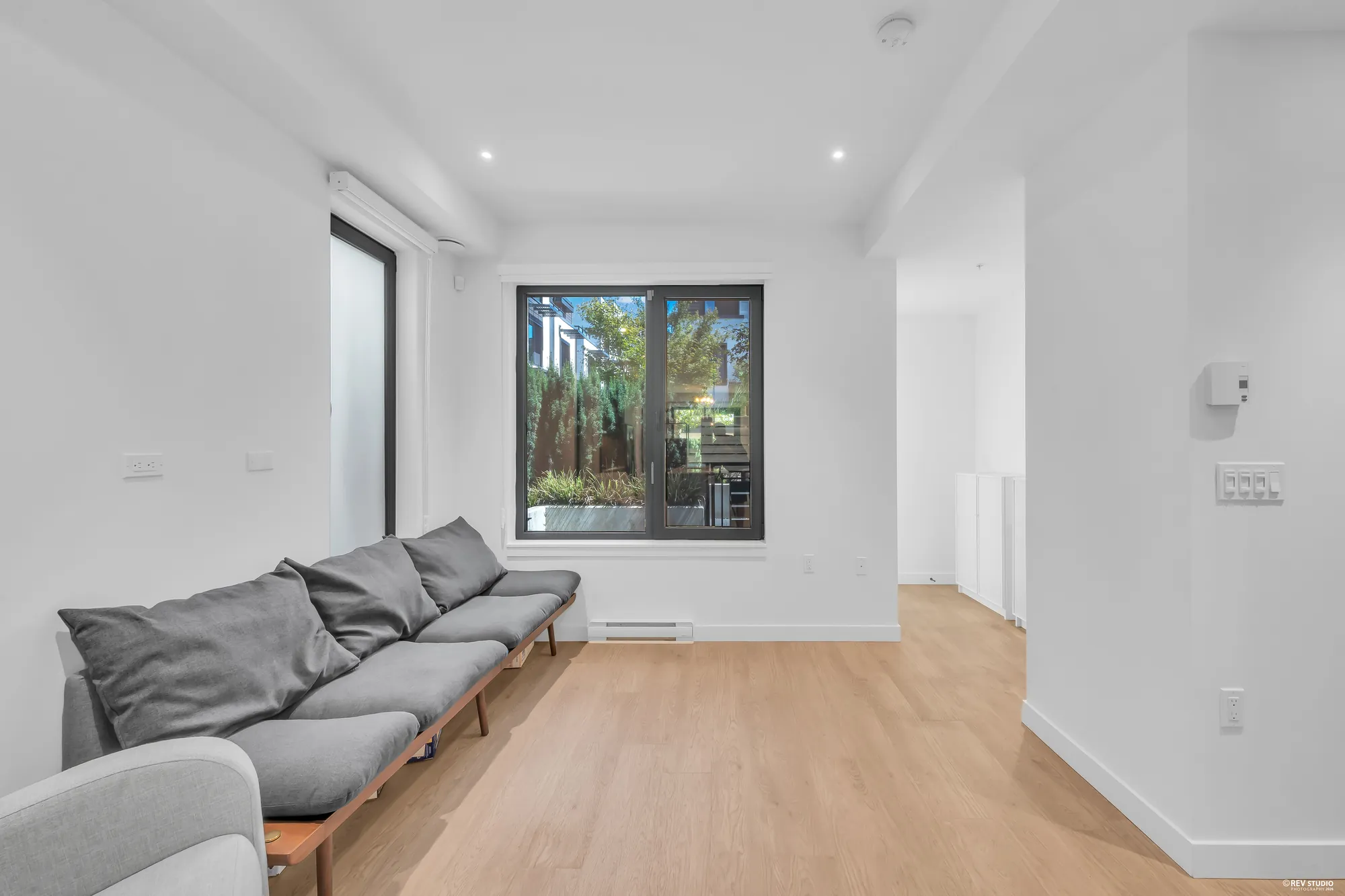 The living room toward the front window, the bench along the side wall, the hall to the foyer at the right