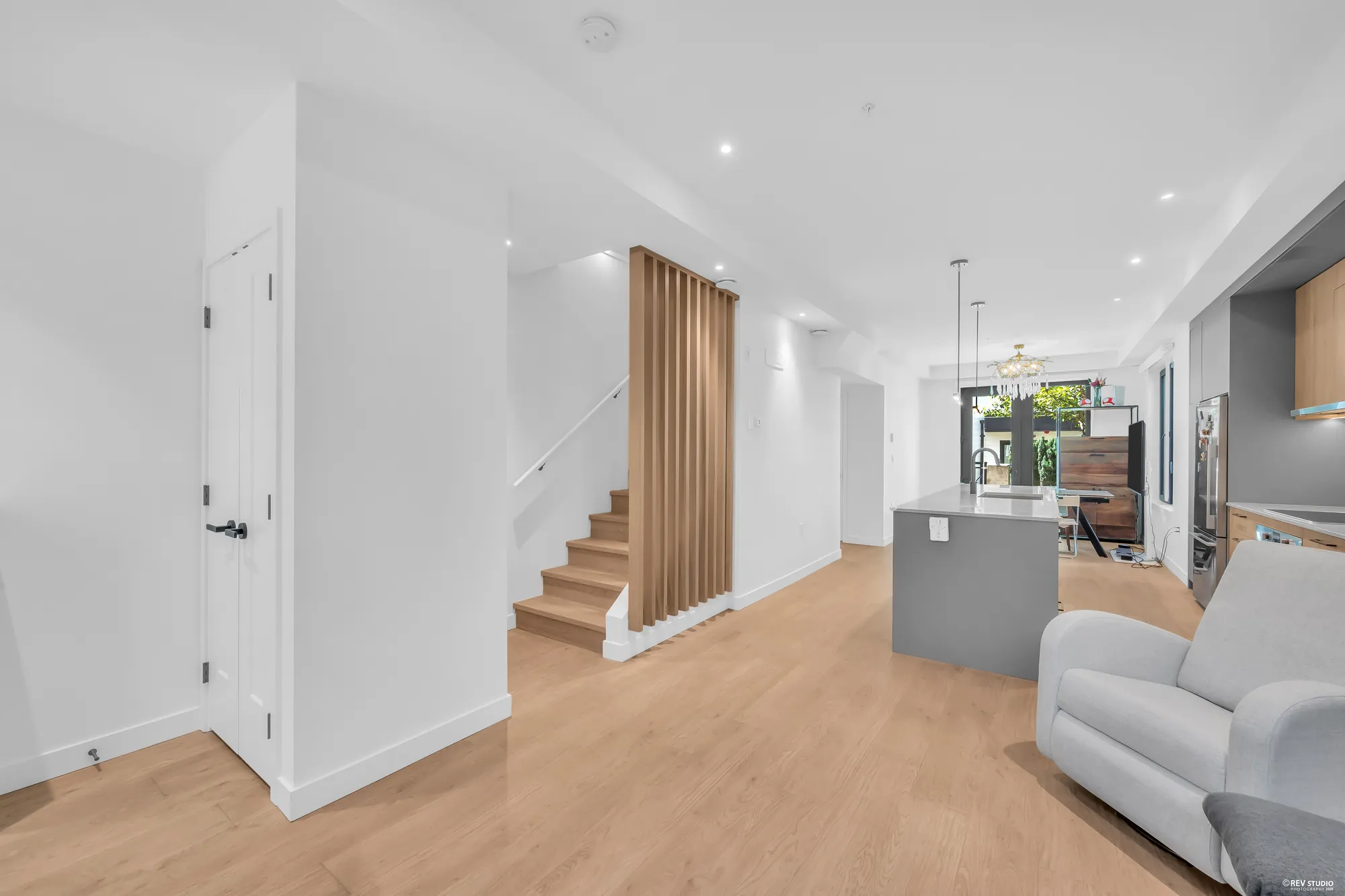From the foyer: a closet door at the left, the stair and its slat screen, the kitchen and the dining room beyond, a recliner
